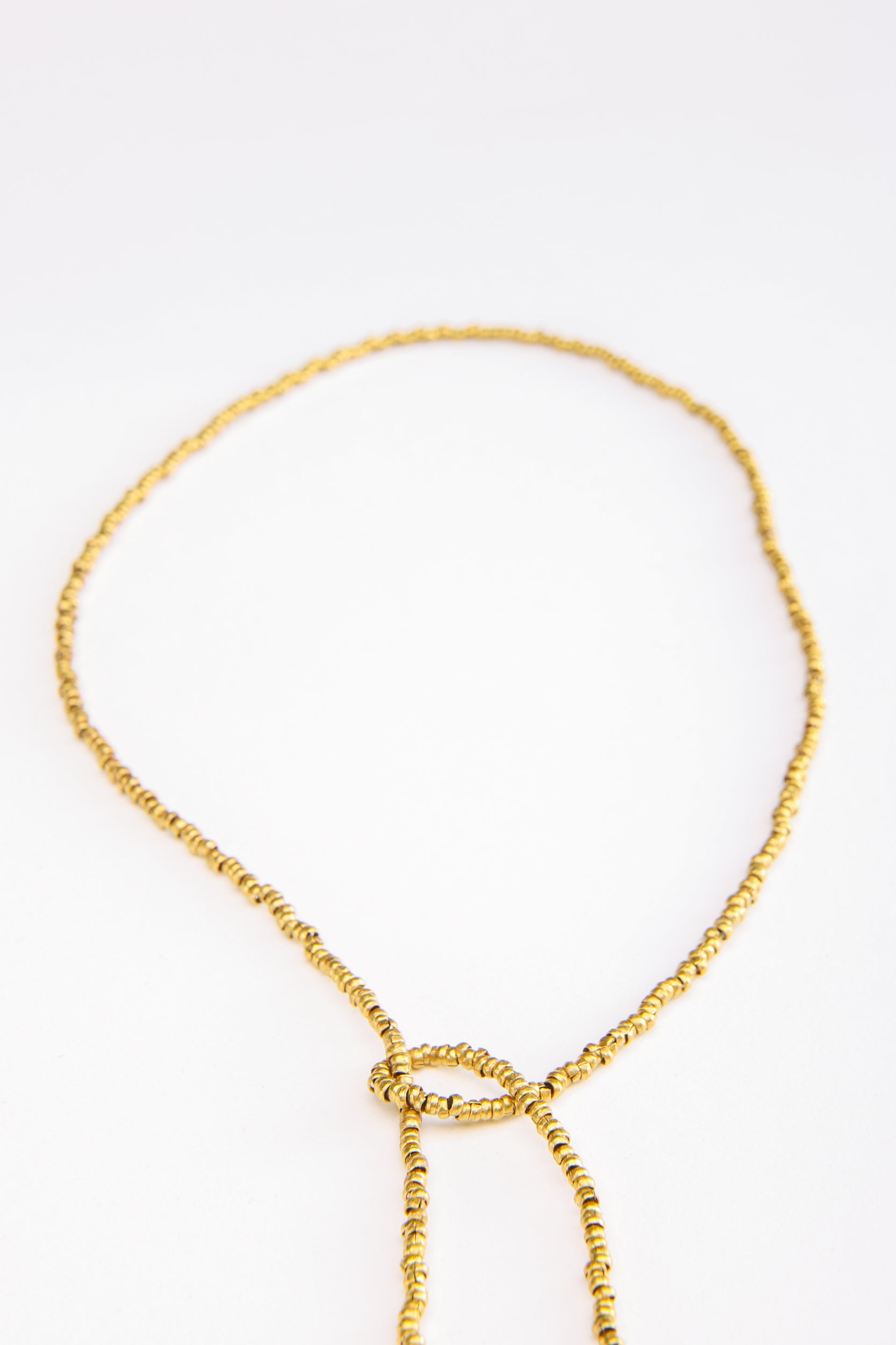 Detailed view of traditional Ethiopian brass beads on handcrafted cross necklace with coral accents