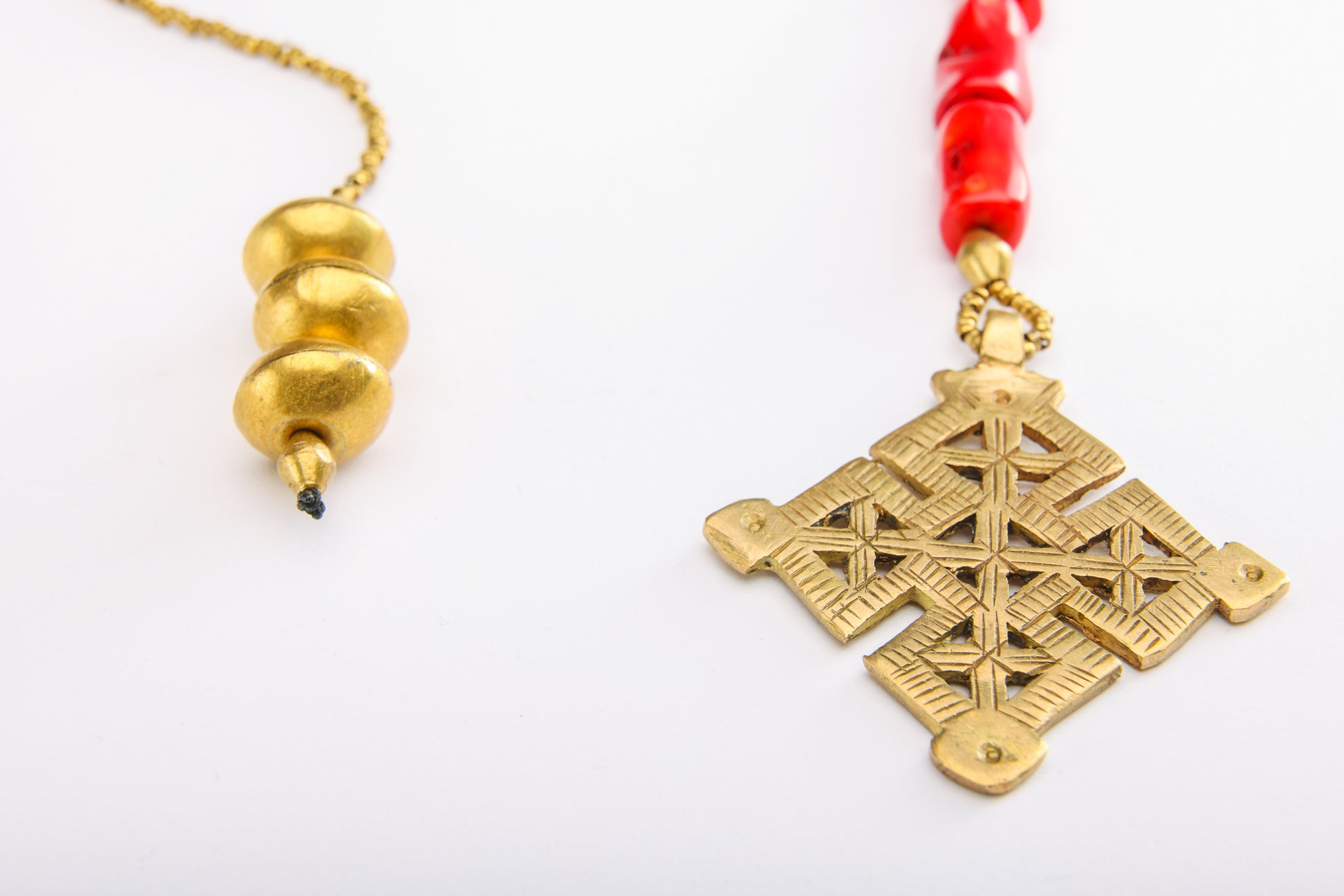 Detailed view of Ethiopian cross pendant with coral beads and weighted end, showcasing craftsmanship